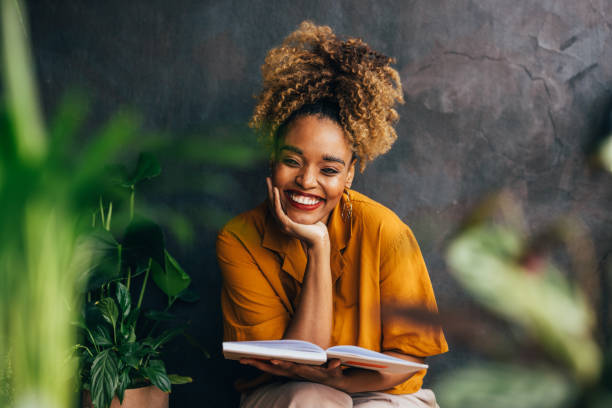 A portrait of a smiling African-American female reading a book while relaxing.